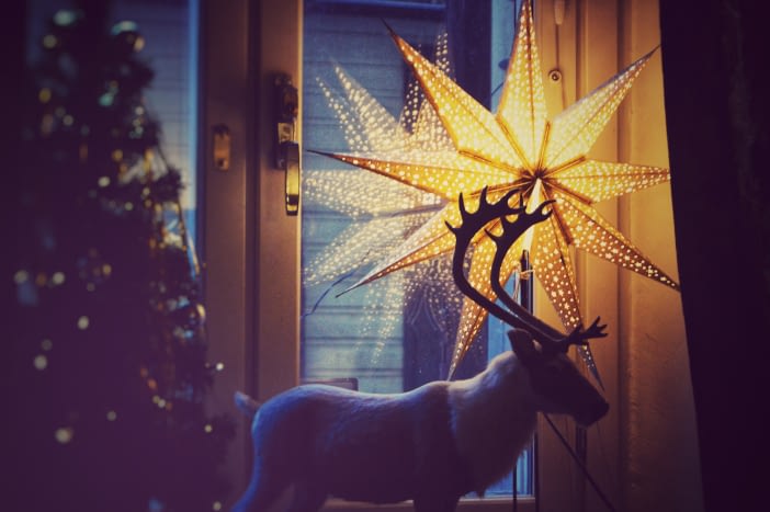 Świąteczna dekoracja okienna z użyciem świecącej gwiazdy i figurki renifera